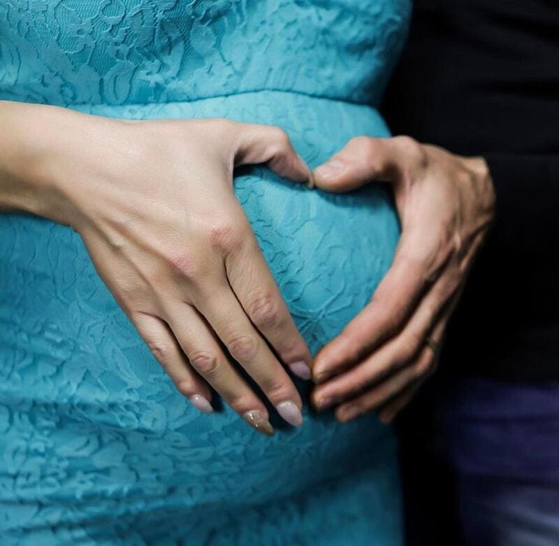 mani a forma di cuore sul pancione